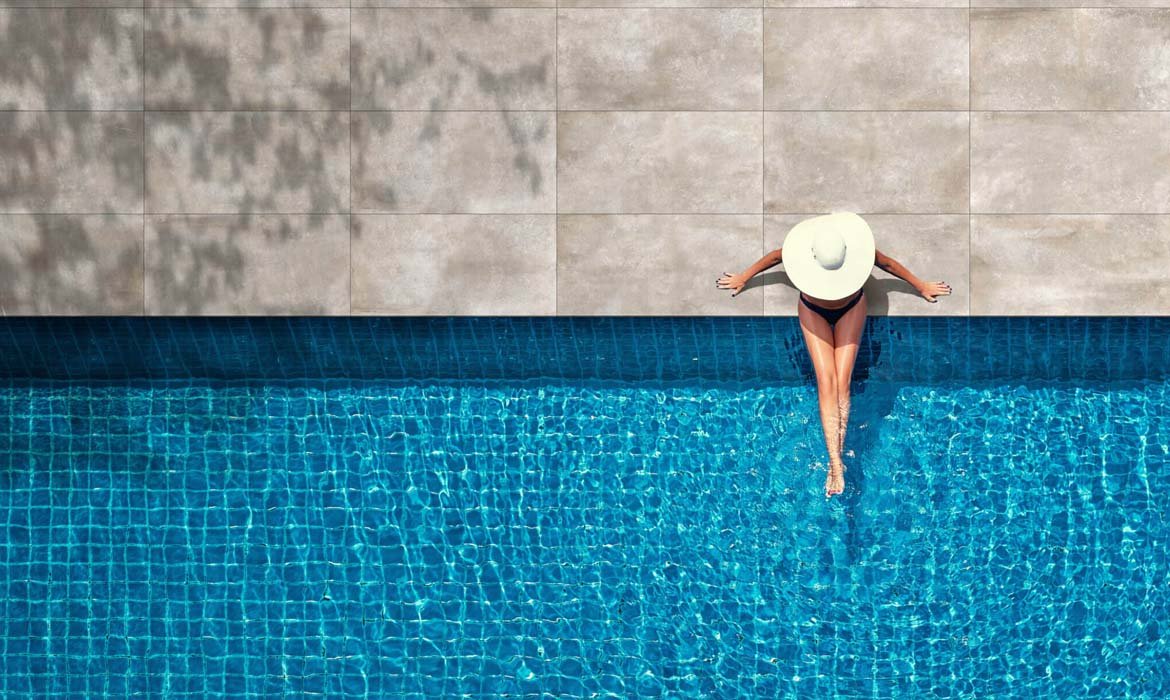 Diseño piscina Valencia, mujer tomando el sol y refrescando sus pies en el agua.