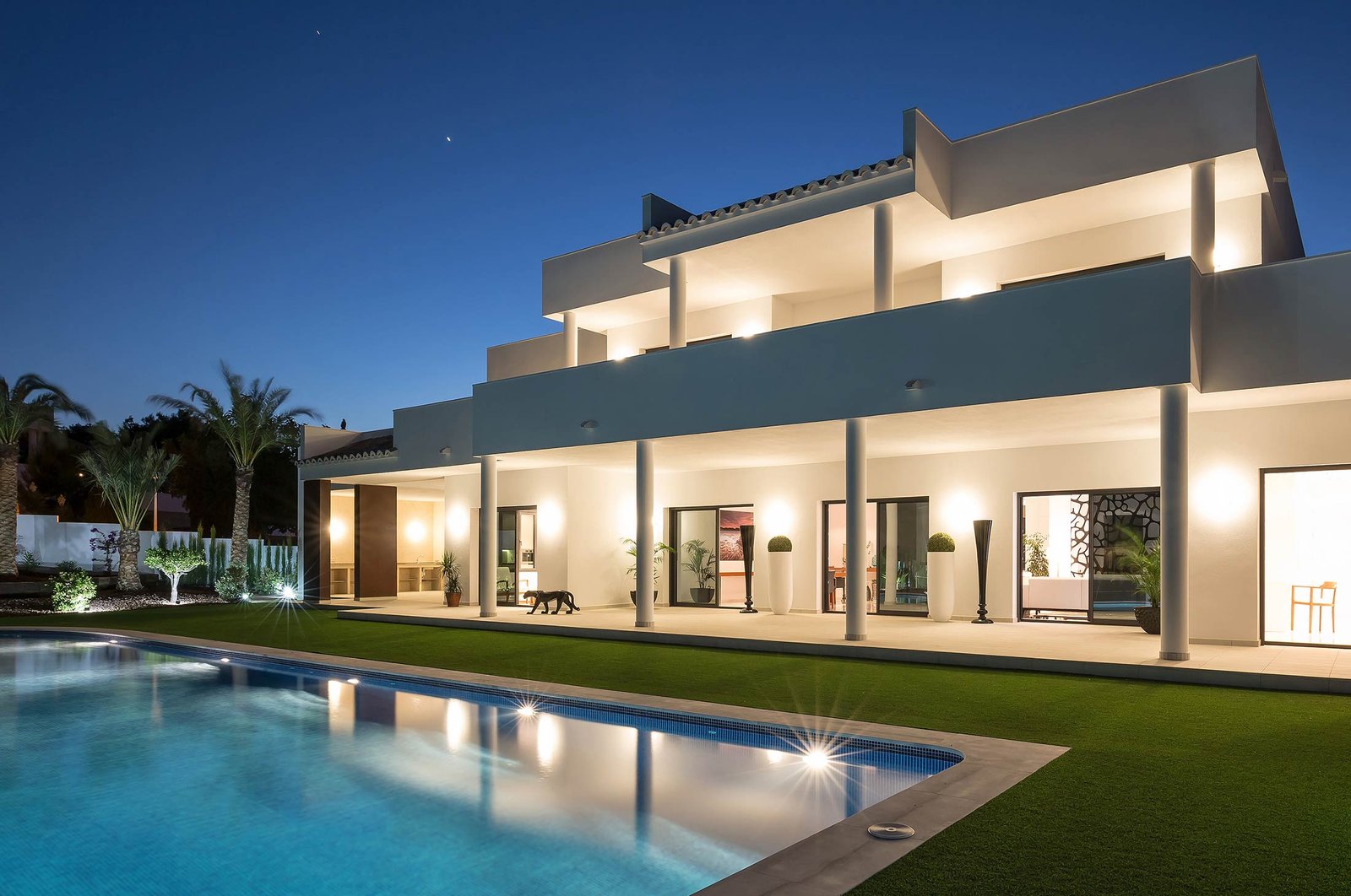 Diseño villa Valencia zona exterior con jardín y piscina iluminada por la noche.