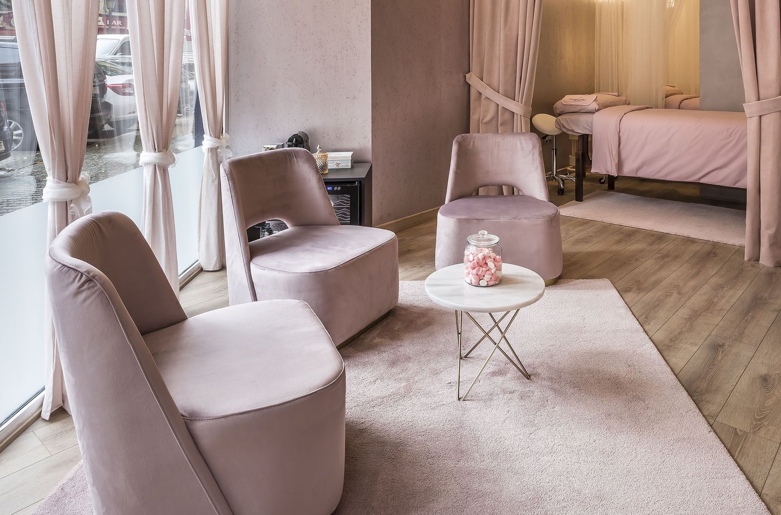 Interiorismo de sala de espera clínica centro de Belleza, acabados con tonos rosas tanto en camas como en butacas y moquetas cortinas.