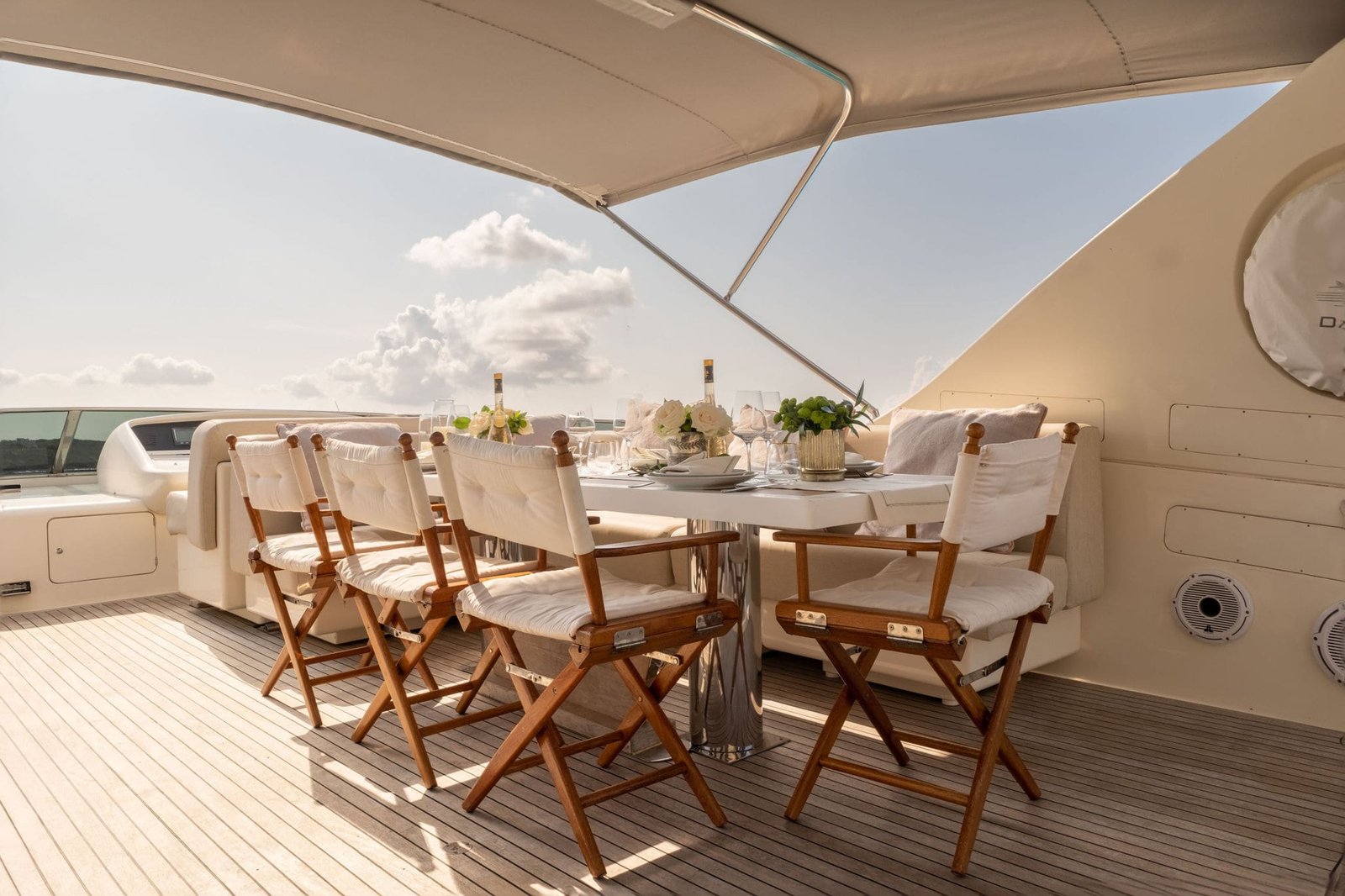 El fly del yate donde presenciamos una mesa decorada al detalle con colores blancos y cálidos junto al juego de sillas. Desde el sitio podemos apreciar el mar turquesa de las aguas de la Isla Ibiza.