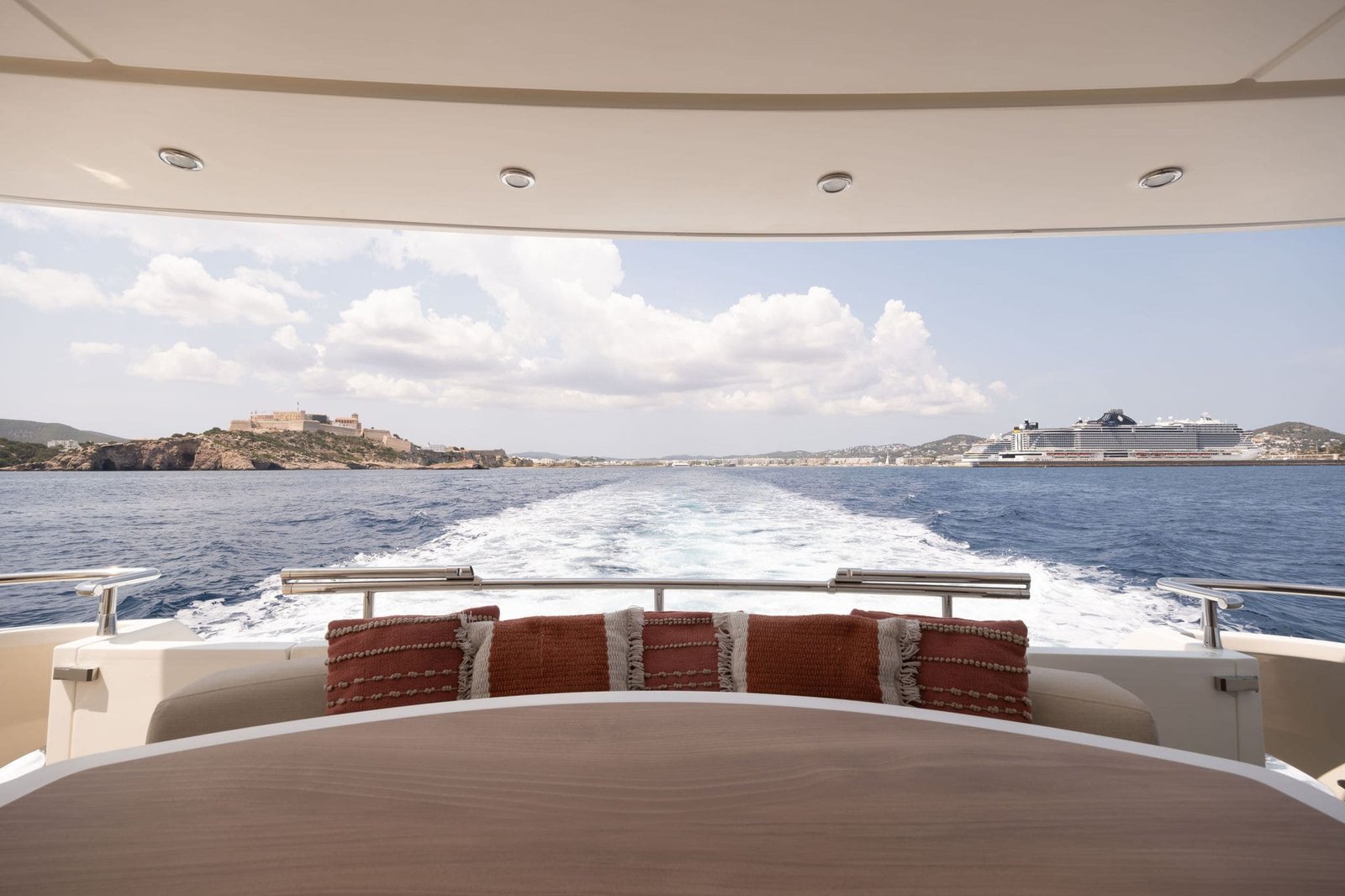 Interiorismo yate barcos lujo diseño exclusividad Las vistas al mar mediterráneo desde la popa del exclusivo y lujoso yate de Daypa Yaths. En la popa encontramos una mesa diseñada por el estudio de Laura Yerpes. El tablero de la esa esta compuesto de tapa de cerámica imitación madera coronada en Corian, los bordes son de canto recto y tablero grueso.