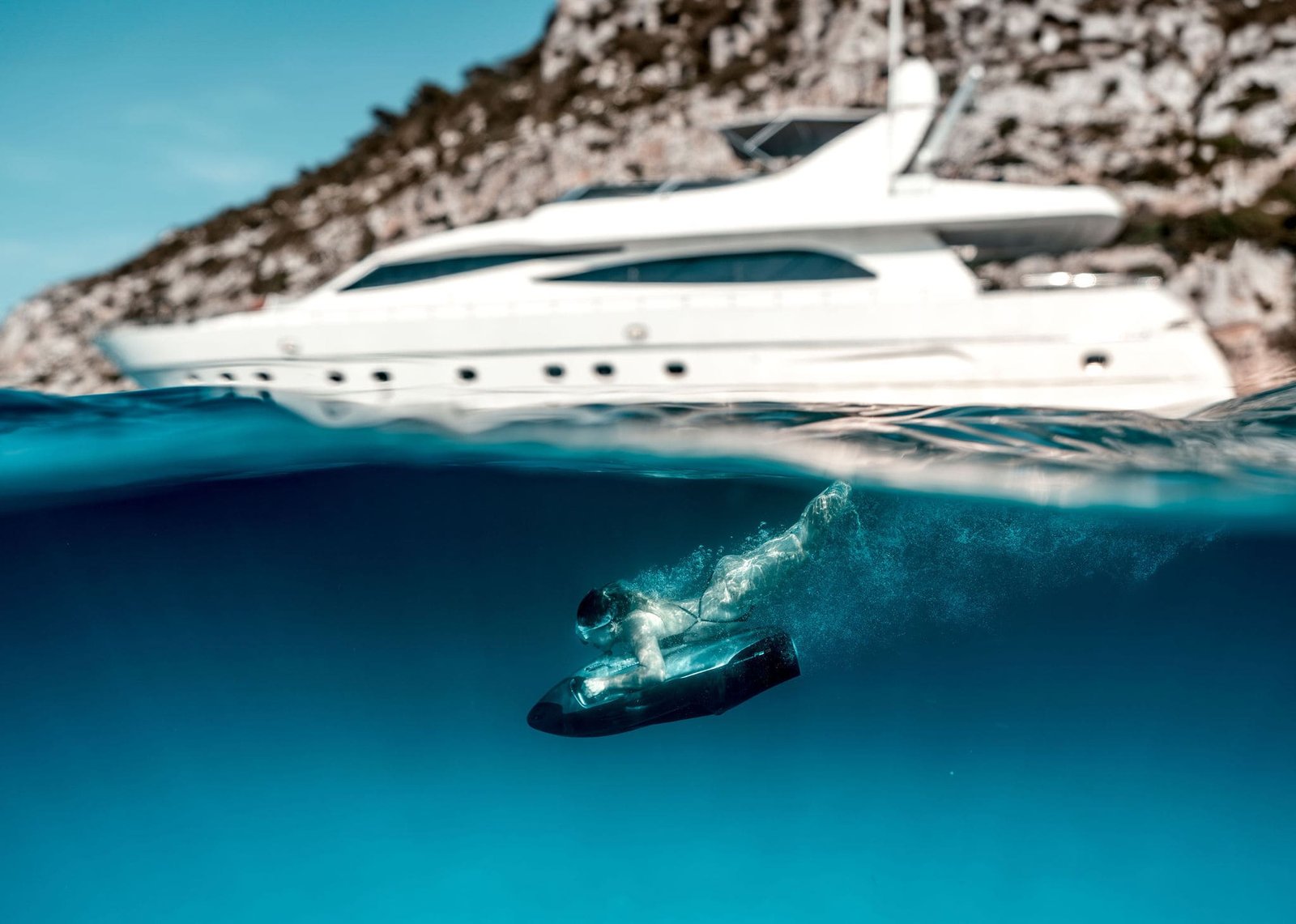 Vemos un yate de lujo junto a una persona que practica submarinismo en las aguas turquesas de una cala de Formentera.